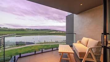 A balcony with a view of a lake, a wooden table, and a sofa.