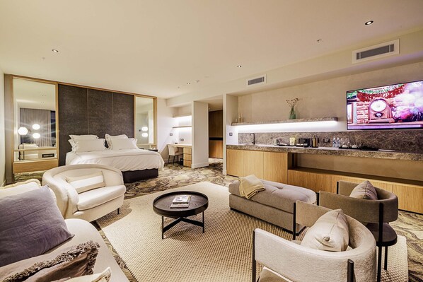 A hotel room with a bed, a sofa, a coffee table, a TV, and a kitchen area. - Re'em Yarra Valley (Melbourne)