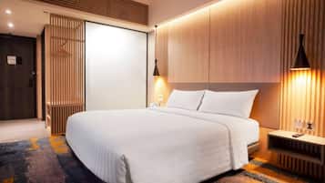 A modern hotel room with a large bed, wooden paneling, and a nightstand with a lamp.