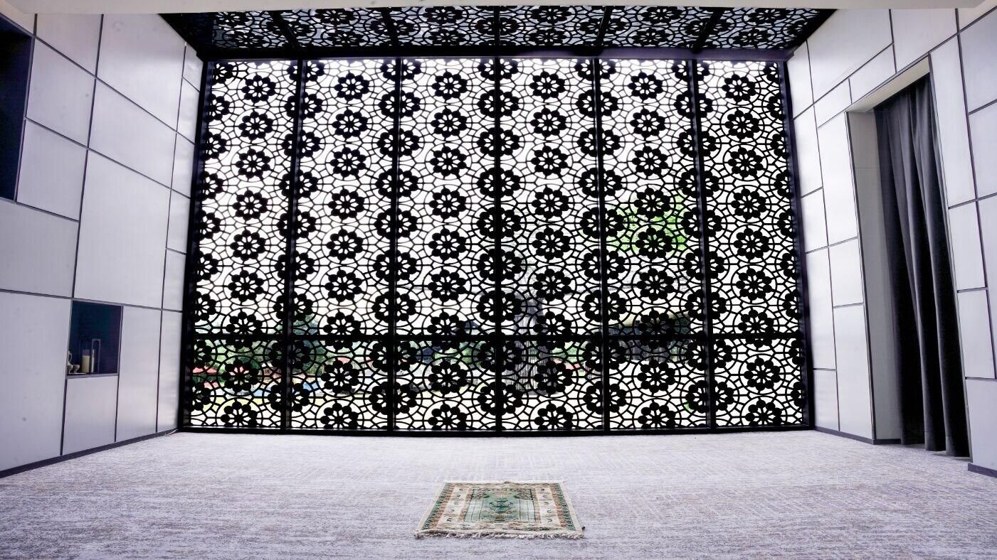 Una habitación con un separador negro estampado, suelo alfombrado y una pequeña alfombra.