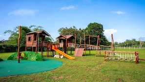 A playground with a slide, climbing structures, and a small wooden house. - Aston Serang Hotel & Convention Center (Serang)
