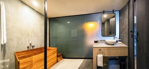 Ein modernes Badezimmer mit einer Holzwanne, einem großen Spiegel und einem Waschbecken mit Handtuchhalter.