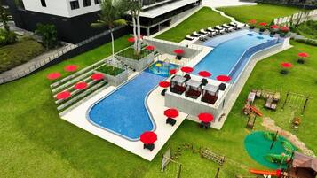 A swimming pool with a children's play area, lounge chairs, and umbrellas.