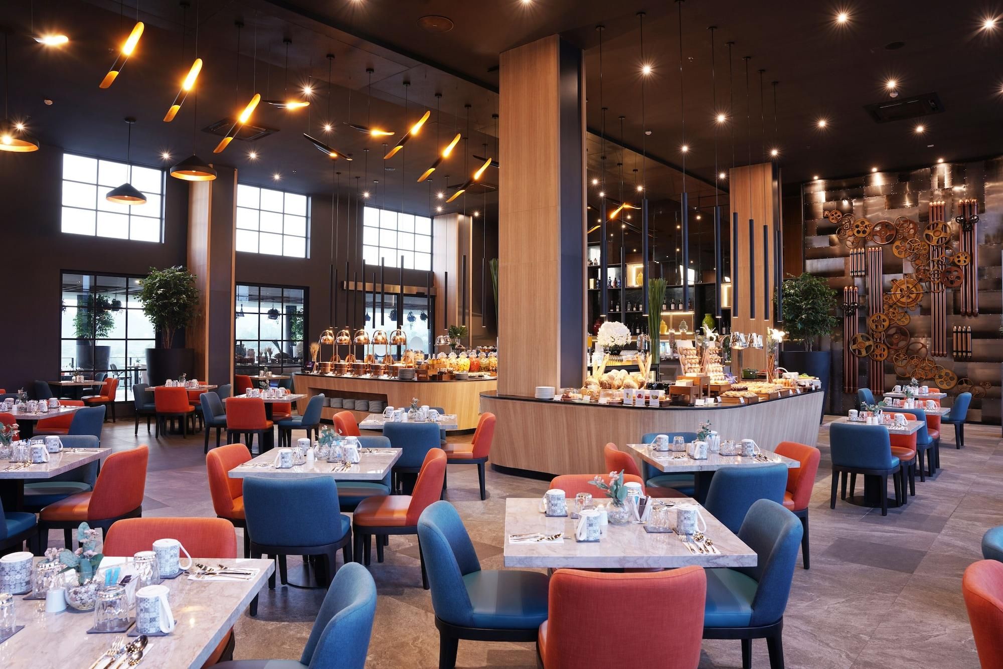 A restaurant with multiple tables and chairs, a buffet counter, and large windows allowing natural light.