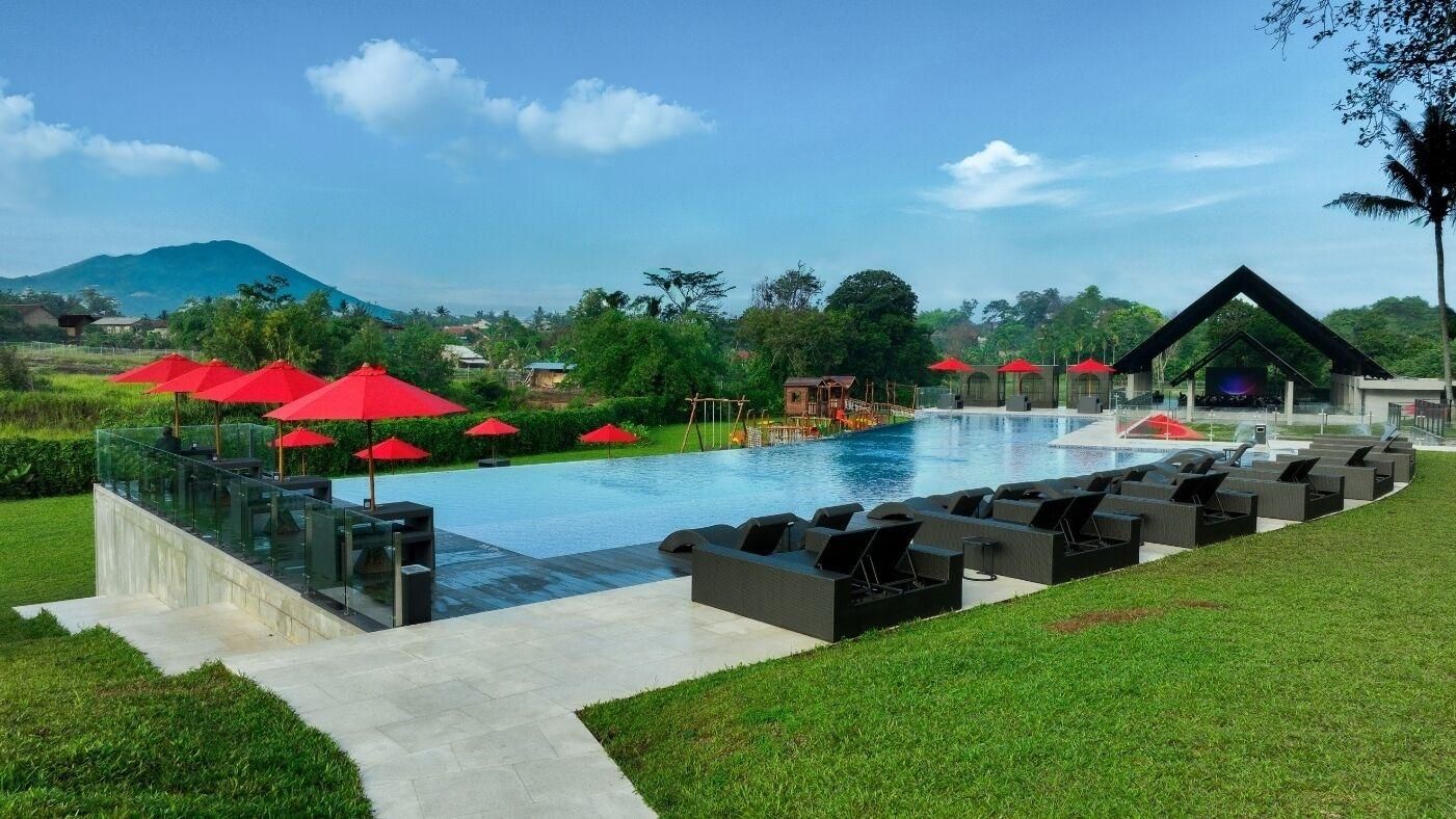 A swimming pool with red umbrellas, lounge chairs, and a glass balustrade.