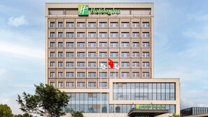 Edificio de hotel Holiday Inn con fachada moderna, múltiples ventanas y un cartel que indica que es un Holiday Inn.
