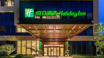 De ingang van een Holiday Inn hotel met een modern ontwerp, met een glazen gevel en een draaideur.