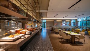 A modern hotel lobby with a buffet area, seating arrangements, and large windows offering views. - Holiday Inn Xian East (Xi'an)