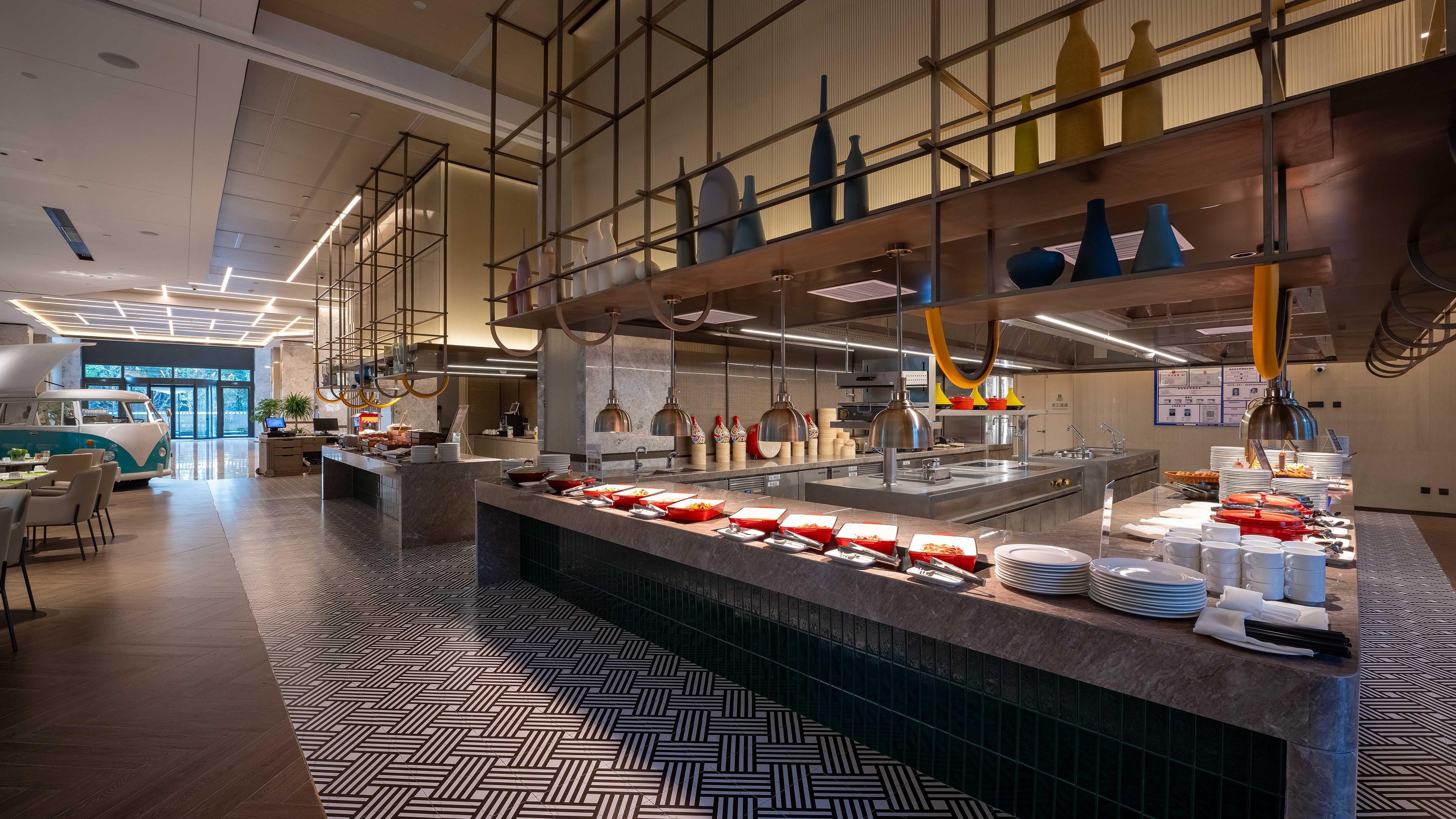 A modern hotel lobby with a central counter, seating area, and a van display.