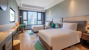 A hotel room with a bed, a desk, a chair, a small table, and a view of the city through large windows. - Holiday Inn Xian East (Xi'an)