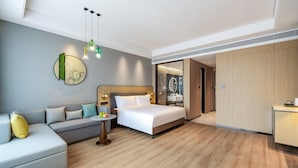 A modern hotel room with a bed, a sofa, a small table with fruit, and a bathroom visible through an open door. - Holiday Inn Xian East (Xi'an)