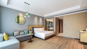 A modern hotel room with a bed, a sofa, a small table with fruit, and a bathroom visible through an open door. - Holiday Inn Xian East (Xi'an)