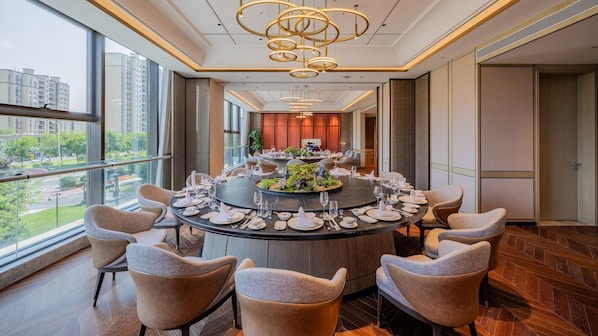 A modern dining room with a round table set for a meal, surrounded by upholstered chairs. - Holiday Inn Xian East (Xi'an)