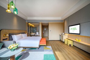 A modern hotel room with a large bed, a desk, and a TV screen displaying hotel information. - Holiday Inn Xian East (Xi'an)