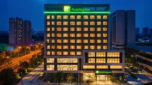 A Holiday Inn hotel with multiple floors, a prominent green sign, and a well-lit facade. - Holiday Inn Xian East (Xi'an)