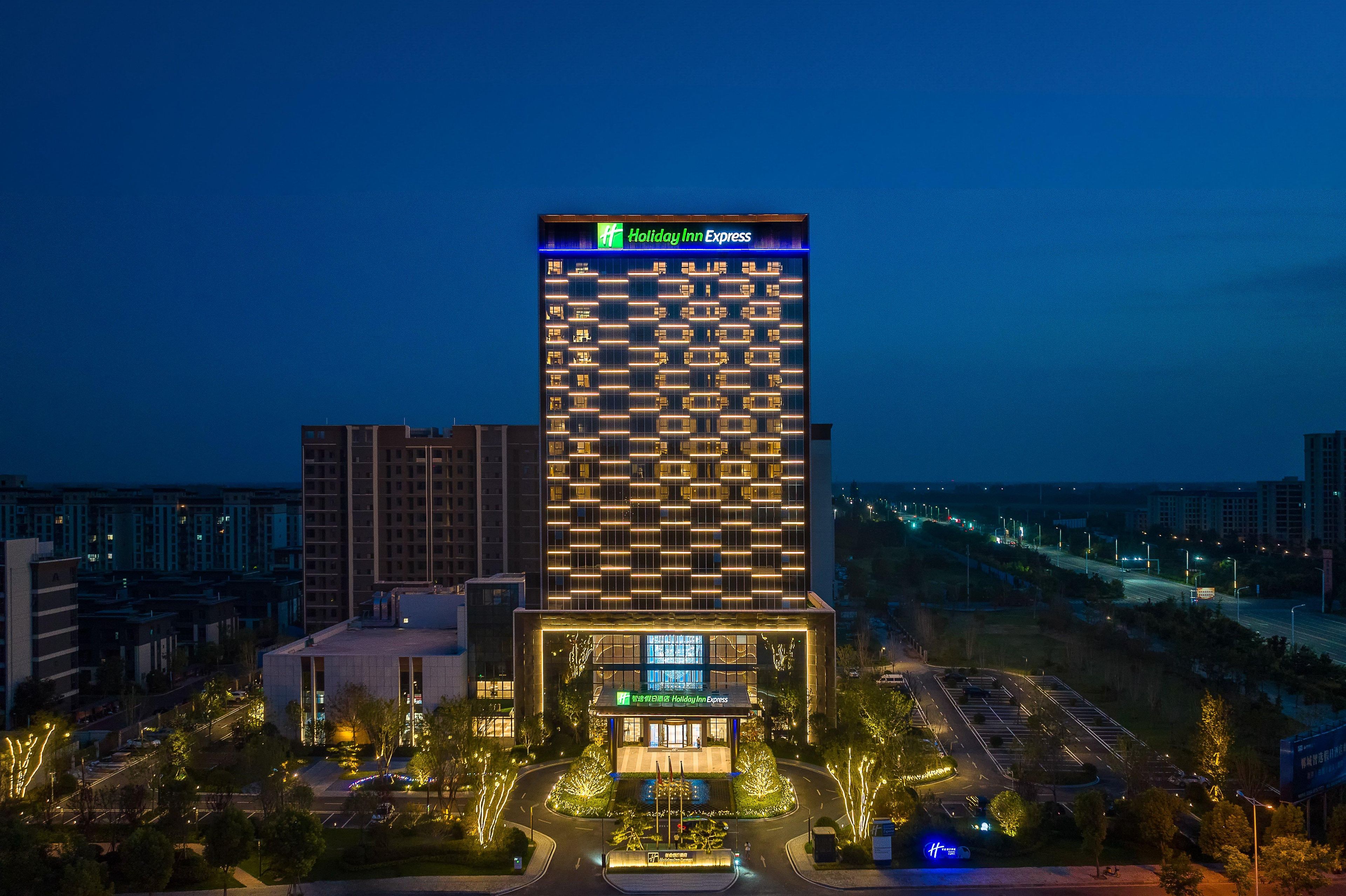 A Holiday Inn Express hotel with a modern design, featuring a prominent sign at the top and a well-lit entrance.