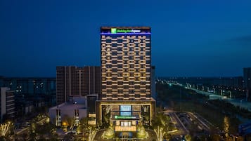 A Holiday Inn Express hotel with a modern design, featuring a prominent sign at the top and a well-lit entrance.