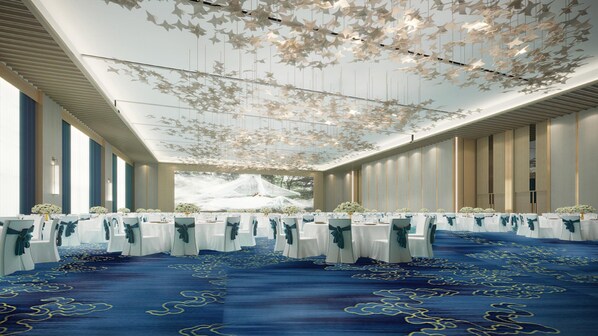 A banquet hall with rows of tables, white tablecloths, and blue chairs.