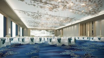 A banquet hall with rows of tables, white tablecloths, and blue chairs.