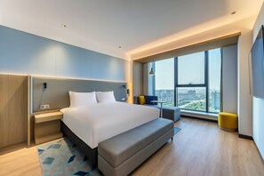 A modern hotel room with a large bed, a seating area, a view of the city, and a large window. - Holiday Inn Express Zhoukou Dancheng An Ihg Hotel (Zhoukou)