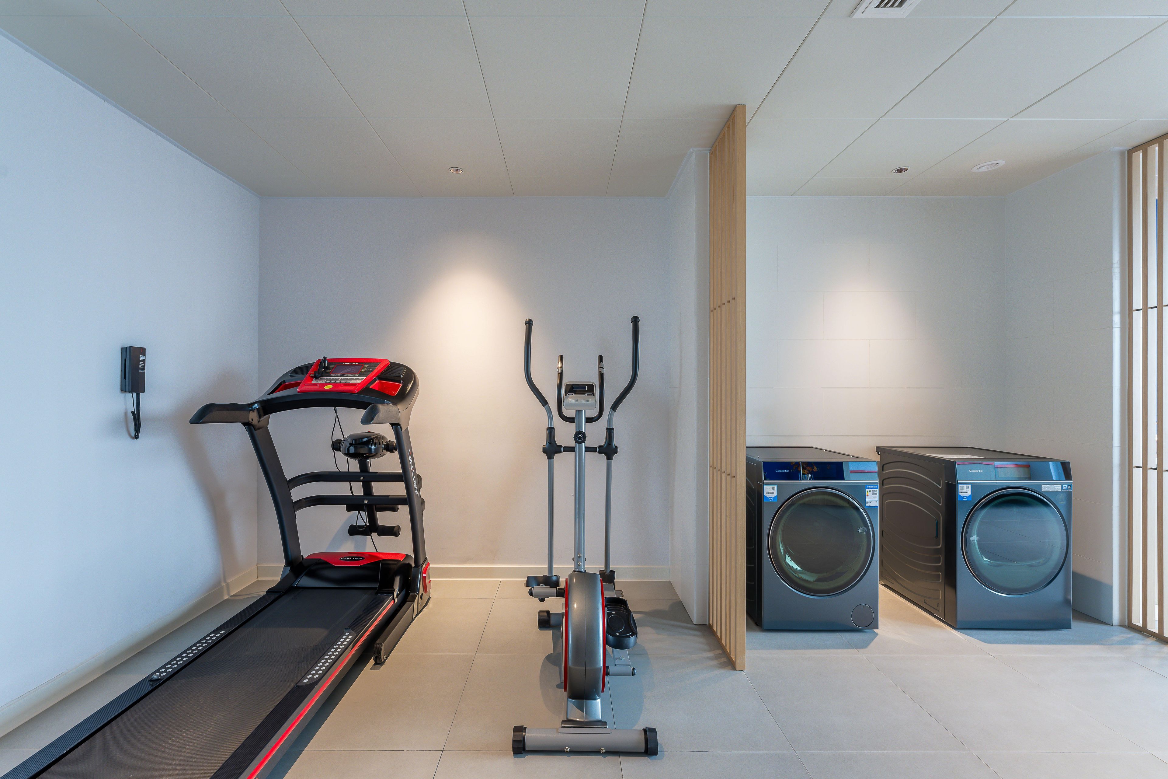 A home gym with a treadmill, elliptical, and washing machine.