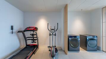 A home gym with a treadmill, elliptical, and washing machine.