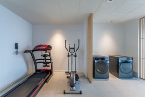 A home gym with a treadmill, elliptical, and washing machine.
