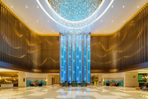 A spacious lobby with a high ceiling, a central vertical light feature, and a reception desk.