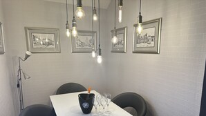 Ein Essbereich mit einem weißen Tisch, schwarzen Stühlen und gerahmten Bildern an der Wand.