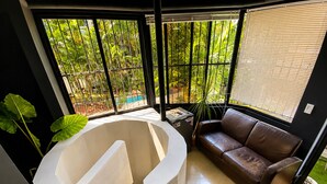 A modern interior with a curved white structure, a brown leather sofa, and large windows with a view of greenery. - Panamá Experience Hostel (Panama City)