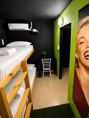 A room with a bunk bed, a desk, a chair, a small plant, and a wall-mounted air conditioner. - Panamá Experience Hostel (Panama City)