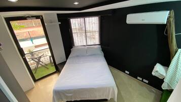 A bedroom with a bed, a window, a door, and a small balcony.