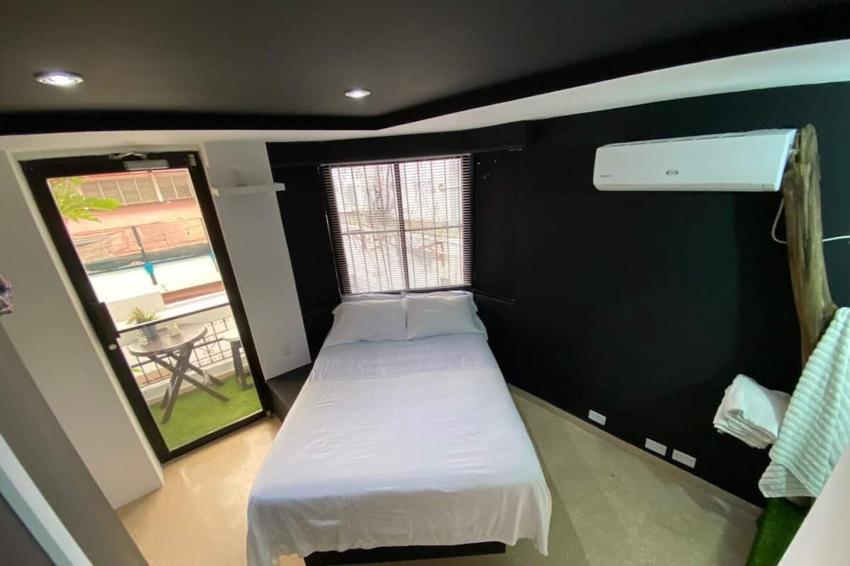 Une chambre à coucher avec un lit, une fenêtre, une porte et un petit balcon.