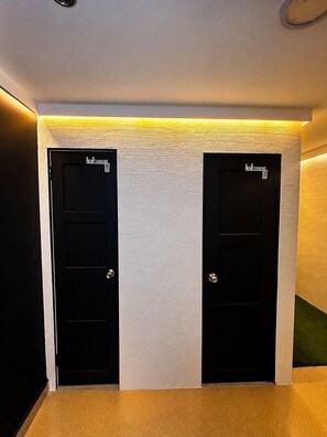 Dos puertas negras con señalización que dice 'Thinking', una pared con textura y un techo con luz amarilla.