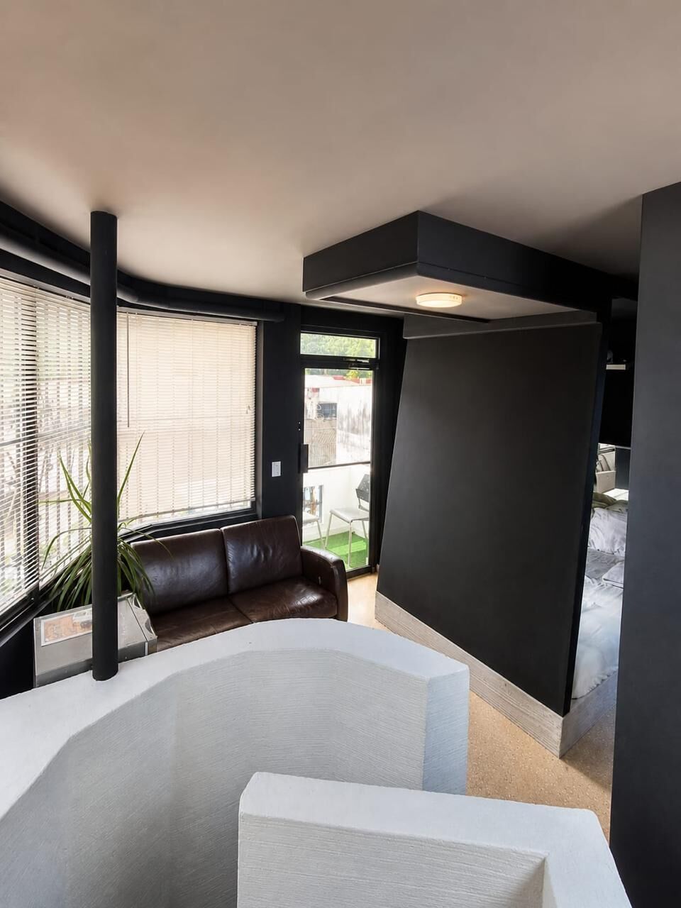 A modern interior with a large white bathtub, a black partition, and a leather sofa.