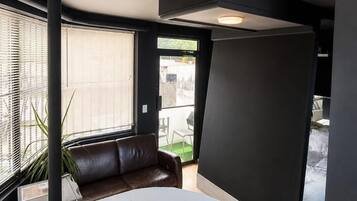 A modern interior with a large white bathtub, a black partition, and a leather sofa.