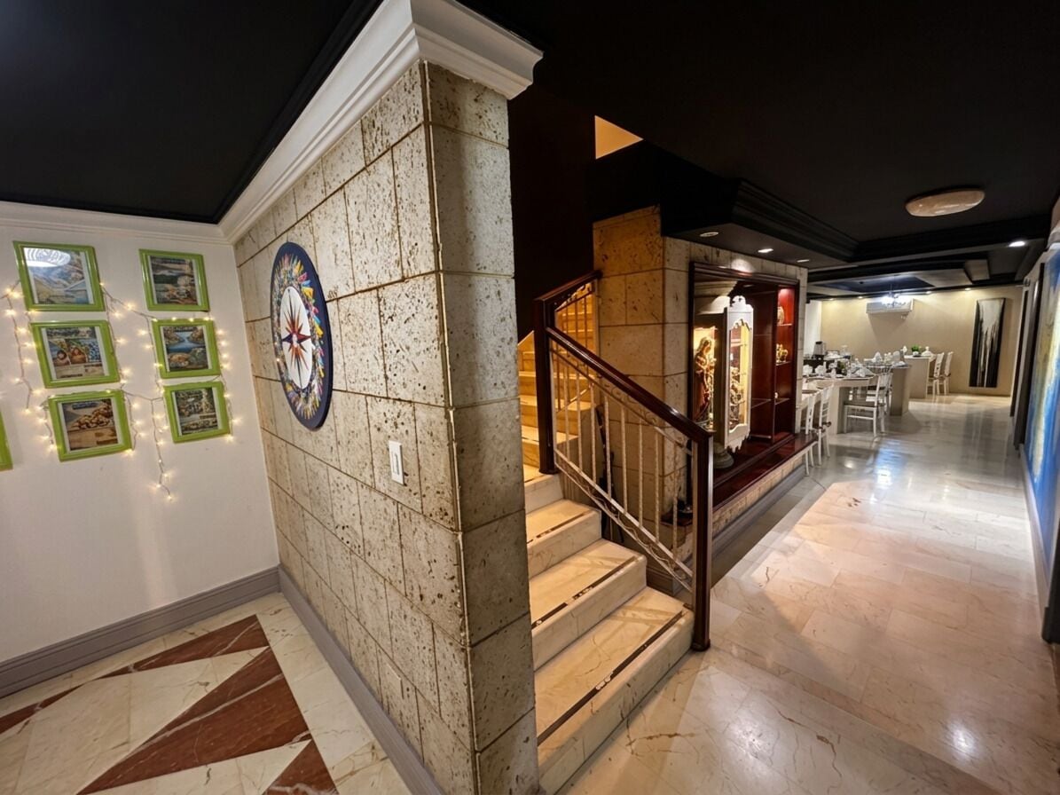 A hotel lobby with a marble staircase, a dining area, and a wall with framed pictures.