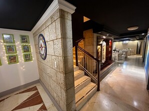 A hotel lobby with a marble staircase, a dining area, and a wall with framed pictures. - Panamá Experience Hostel (Panama City)