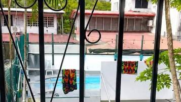 Zona de piscina con puerta y vistas a un edificio y palmeras.