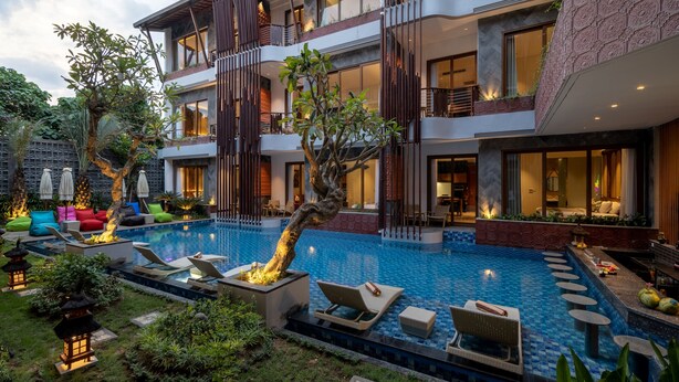 A modern hotel with a large outdoor swimming pool, multiple balconies, and lush landscaping. - Mokko Suites Batubelig (Keroboken Kelod)
