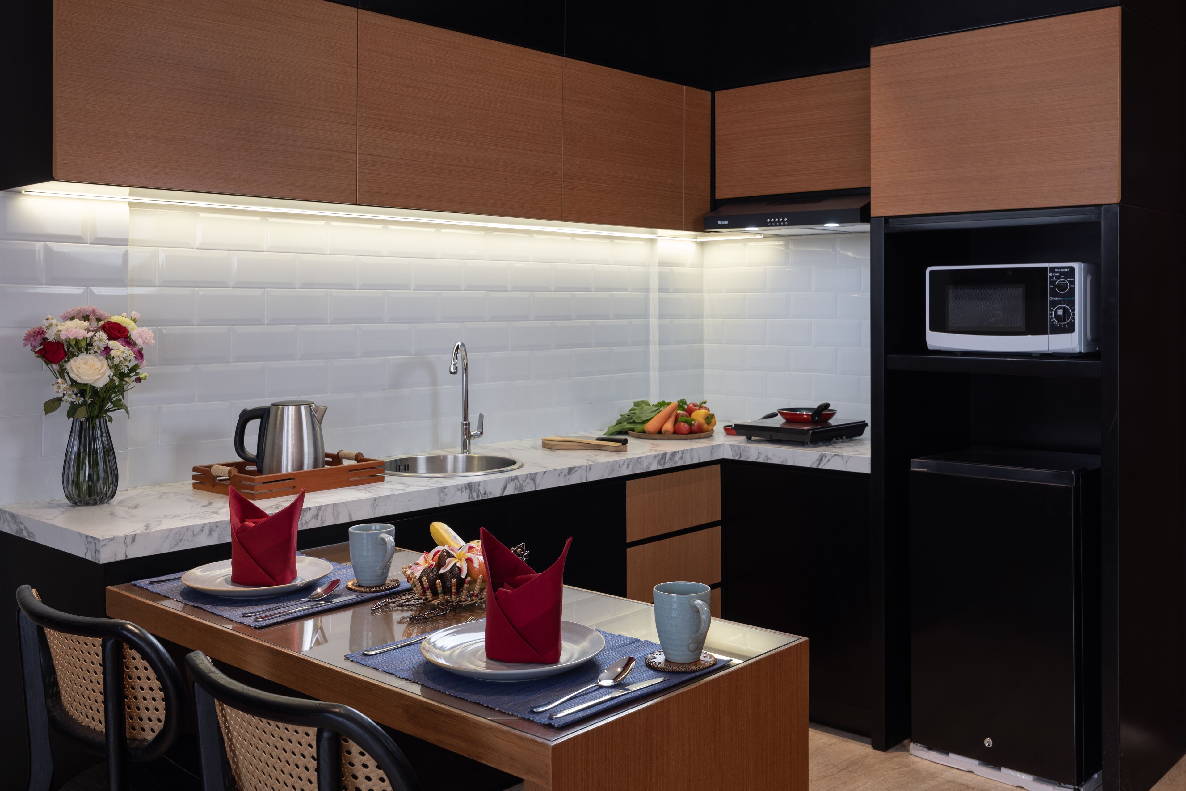 A modern kitchen with a built-in microwave, a sink, and a dining area with a table set for two.