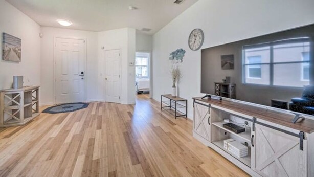 A spacious living room with hardwood flooring, a large TV, and a wooden coffee table. -  Home with Private Heated Pool 10 Mi to Disney World and other Major Parks! (Davenport)