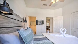 A hotel room with a bed, a headboard, a wall-mounted lamp, a ceiling fan, and a television. -  Home with Private Heated Pool 10 Mi to Disney World and other Major Parks! (Davenport)