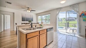 A kitchen with wooden cabinets, a dishwasher, and a large window. -  Home with Private Heated Pool 10 Mi to Disney World and other Major Parks! (Davenport)
