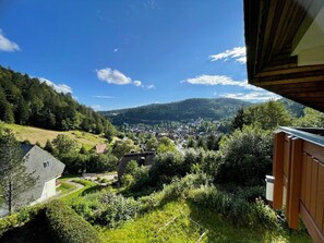 A view of a town from a high vantage point, surrounded by greenery and hills.
