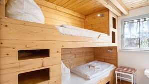 Dormitorio con literas, paredes de madera y una ventana.