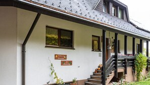 A building with a sloped roof, a staircase leading to a porch, and potted plants.