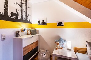 A child's room with a white desk, a teddy bear, a lamp, and wall art depicting animals. - Ferienwohnung with 40qm (Dachsberg)