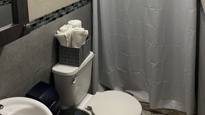 A bathroom with a toilet, a sink, and a shower curtain. - Pompeii Apartment (Aguada)