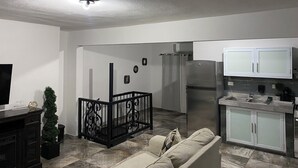 A modern kitchen with a refrigerator, cabinets, and a dining area with a sofa. - Pompeii Apartment (Aguada)